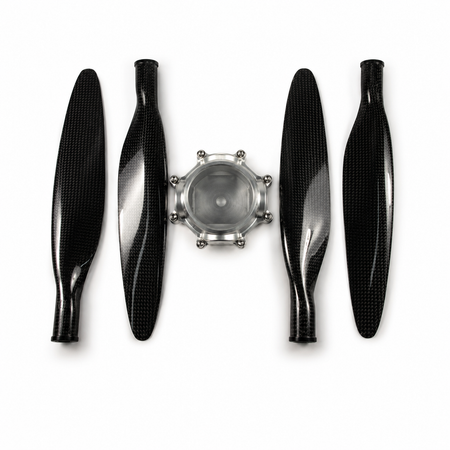 Four black carbon fiber propeller blades arranged symmetrically around a silver metal central hub on a white background.