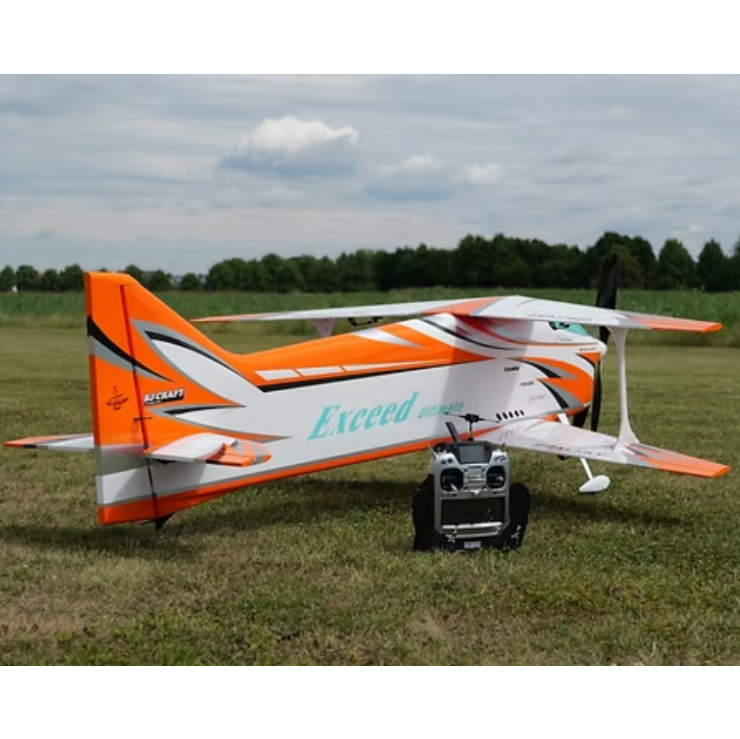Orange and white RC airplane on grass with control gear nearby