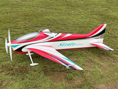 Red and white model airplane with 'Strato' branding on a grassy field