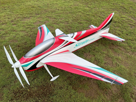 Red, white, and green model airplane on grass