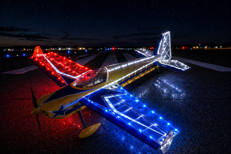 Small airplane with colorful LED lights on a runway at night