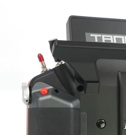 Close-up of a black mechanical device with red buttons on a white background, featuring the brand 'TAN'.